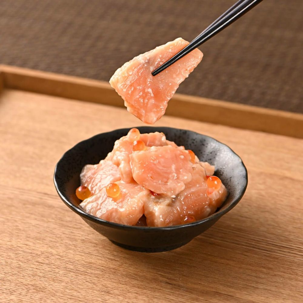 お皿に盛られたサーモン塩麹漬けを箸で持ちあげている。